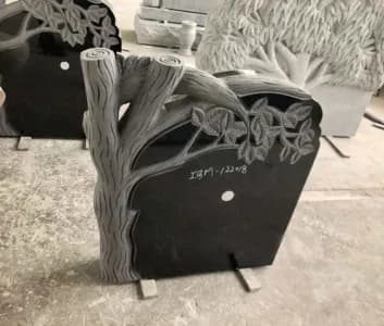 Black granite memorial with a carved tree and leaves